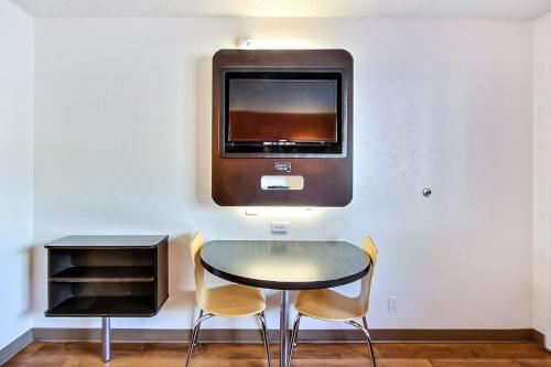 a table with two chairs and a tv on a wall at Motel 6-Campbell, CA - San Jose in Campbell