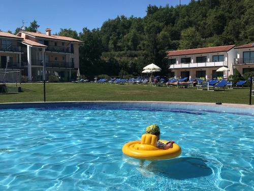 a person in a raft in a swimming pool at Bran & Denise Residence in Costermano sul Garda
