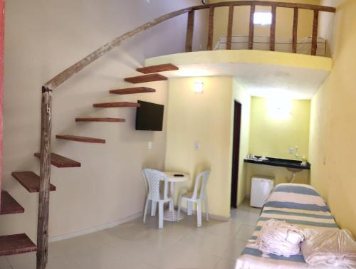 um quarto com uma escada, uma cama e uma mesa em Flats da Paz Maracajaú em Maracajaú