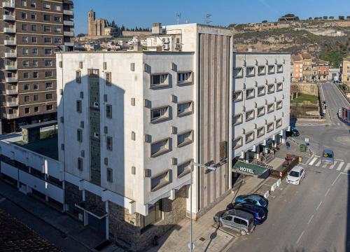 un grand bâtiment blanc avec des voitures garées dans une rue dans l'établissement HOTEL JAUME D'URGELL, à Balaguer