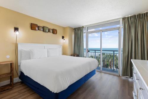 a bedroom with a bed and a large window at Atlantica Towers Condo w Balcony by Hosteeva in Myrtle Beach