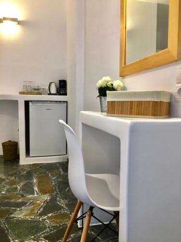 a kitchen with a white counter and a white chair at Nostos Studios in Parikia
