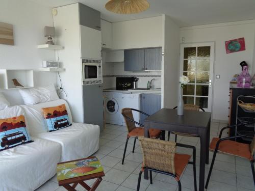 a room with a bed and a table and a kitchen at Appartement La Corniche Vue océan in Mimizan-Plage