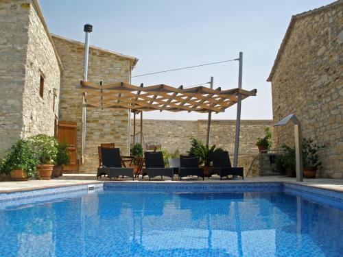 a swimming pool with chairs and a wooden pergola at Lito House in Skarinou