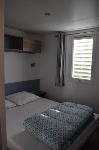 une petite chambre avec un lit et une fenêtre dans l'établissement Camping La Croix Badeau, à Soulaines-Dhuys