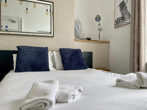 a white bed with blue pillows and towels on it at Brighton Black Hotel & Hot Tubs in Brighton & Hove