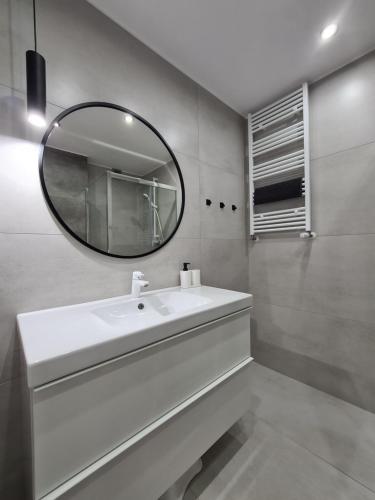 a bathroom with a white sink and a mirror at Loft Apartamenty w Sarbinowie in Sarbinowo