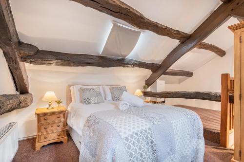 a bedroom with a white bed and wooden ceilings at Cottage 2, Old Farmhouse Mews in Braithwaite