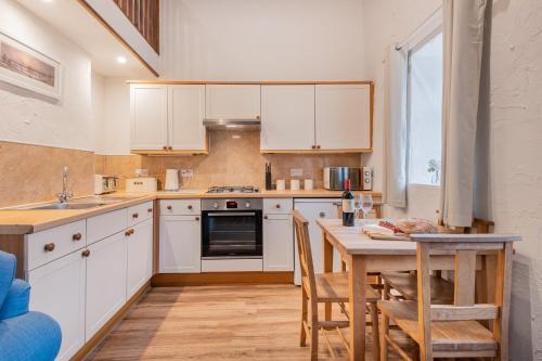 a kitchen with white cabinets and a table with chairs at Cottage 2, Old Farmhouse Mews in Braithwaite