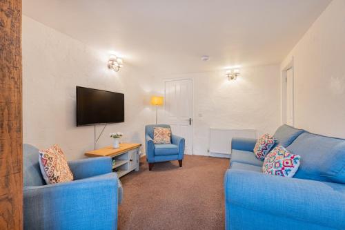 a living room with two blue couches and a television at Cottage 2, Old Farmhouse Mews in Braithwaite