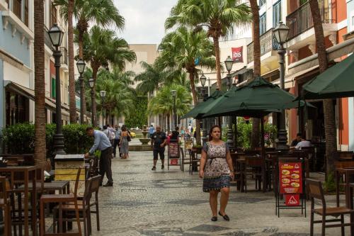 a woman walking down a street with tables and chairs at ibis Rio de Janeiro Nova America in Rio de Janeiro