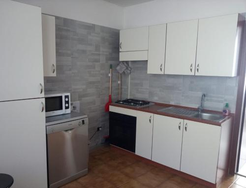 una pequeña cocina con armarios blancos y microondas en Casa Federica, en Molina di Ledro