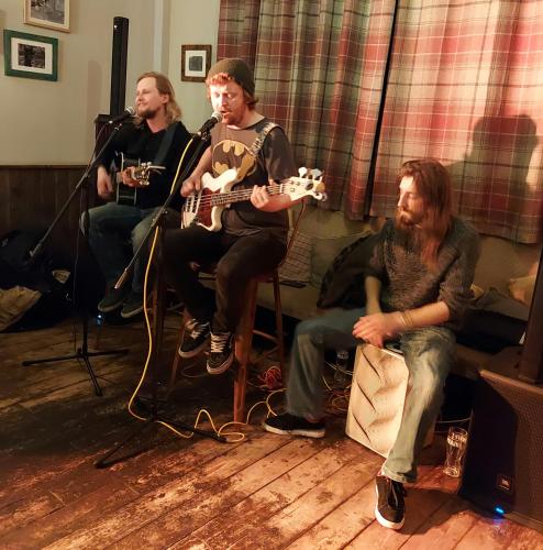 a group of three men sitting in a room playing guitars at Trawden Arms Community Owned Pub in Winewall