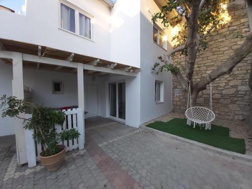 a white house with a tree and a white bench at Antonios 1 in Matala