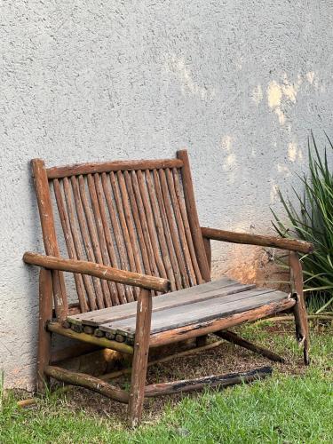 a wooden bench sitting in the grass next to a wall at White Linen Guesthouse in Tierpoort