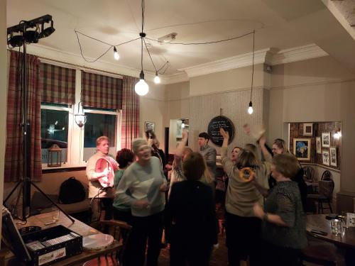 a group of people standing in a room with their hands in the air at Trawden Arms Community Owned Pub in Winewall