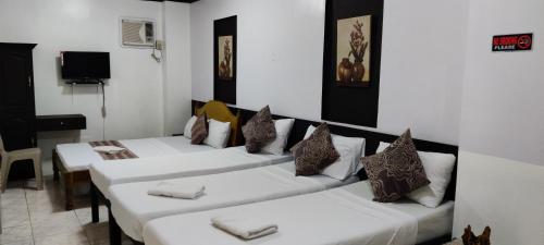 a room with three beds with pillows on them at Center Parkway Pension House in Kalibo