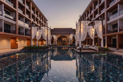 a hotel swimming pool with umbrellas in a courtyard at Laguna Grand Hotel & Spa Songkhla in Songkhla