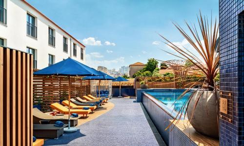 una piscina con sedie a sdraio e ombrelloni accanto a un edificio di The Lodge Hotel a Vila Nova de Gaia
