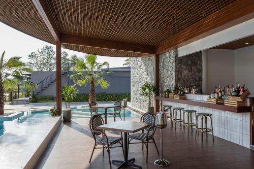 an outdoor bar with tables and chairs next to a swimming pool at Laguna Grand Hotel & Spa Songkhla in Songkhla