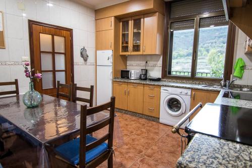 cocina con mesa, sillas y nevera en Casa Charo Prexigueiro, en Ribadavia