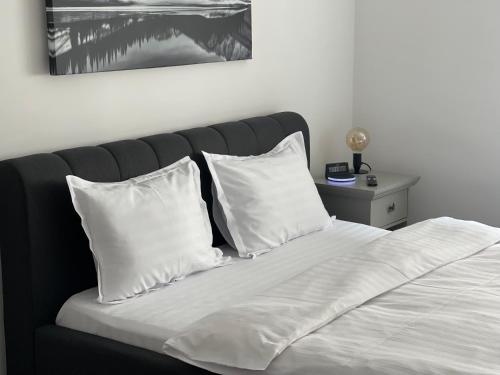 a bed with white pillows and a black headboard at Maple Lodge Apartments in Braşov