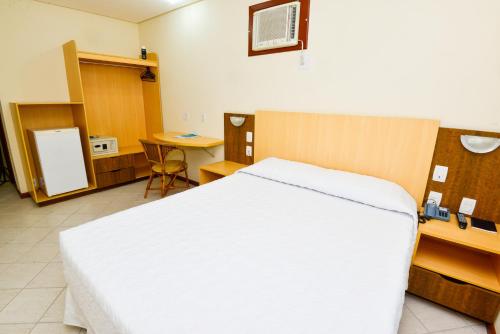 a bedroom with a bed and a desk and a table at Hotel Plaza Mar in Vila Velha