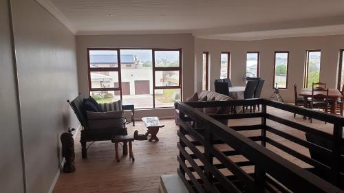 a living room with chairs and a balcony with windows at Stonehouse on Main in Struisbaai