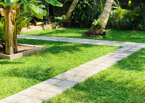 a stone walkway in the grass near a tree at Manel Villa in Bentota