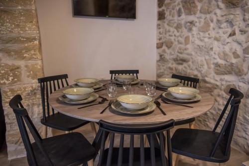 a wooden table with chairs and plates and wine glasses at Dinas's Cottage Ideal Base for Balos and Elafonisi in Kaloudhianá