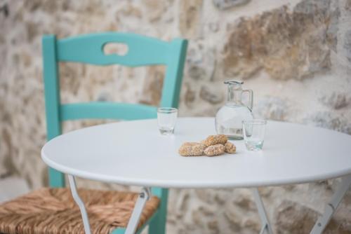 a white table with two chairs and a bottle and glasses at Dinas's Cottage Ideal Base for Balos and Elafonisi in Kaloudhianá