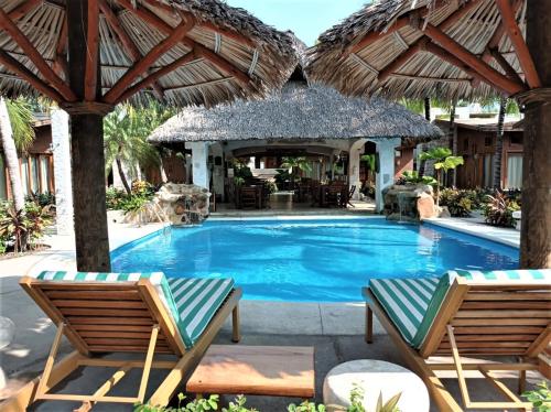 een zwembad met 2 stoelen en een parasol bij Hotel Casa de Lirio Diamante in Acapulco