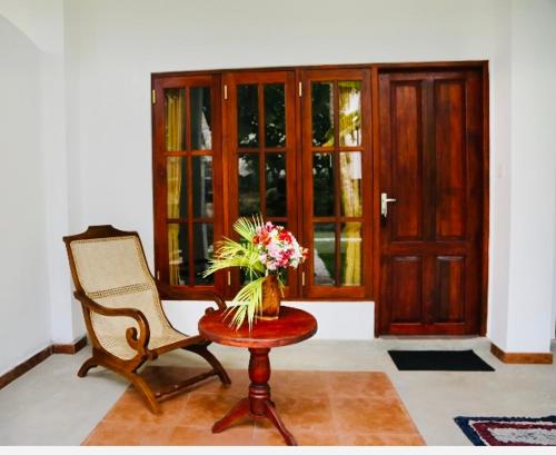 a chair and a table with a vase of flowers at Manel Villa in Bentota