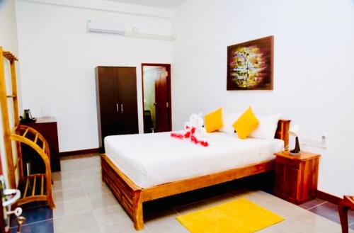 a bedroom with a bed with white sheets and yellow pillows at Manel Villa in Bentota