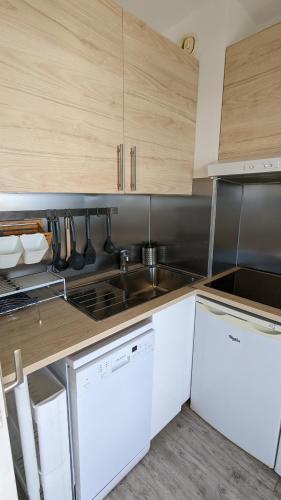 une cuisine avec des appareils électroménagers blancs et des armoires en bois dans l'établissement Cnossos, à Cannes