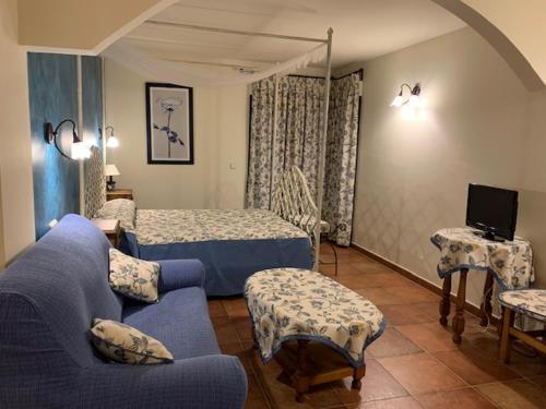 a living room with a blue couch and a bed at Hotel Langa in Cerezo de Abajo