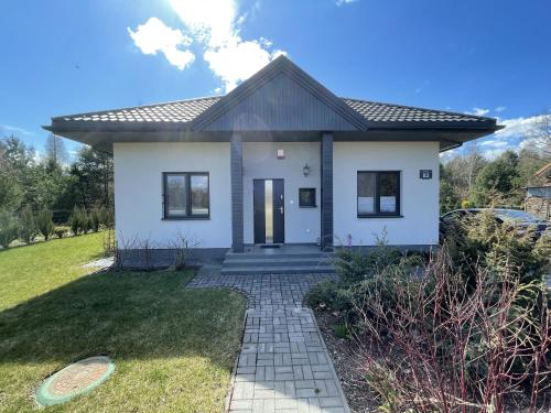 a small white house with a pathway at Dom na skraju lasu in Arciechow