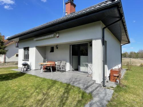 a house with a patio with a table and chairs at Dom na skraju lasu in Arciechow