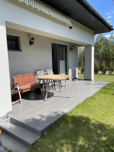 a patio with a wooden table and a bench at Dom na skraju lasu in Arciechow