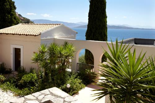 une maison blanche avec vue sur l'eau dans l'établissement Sunshine Corfu Hotel And Spa, à Nisakion