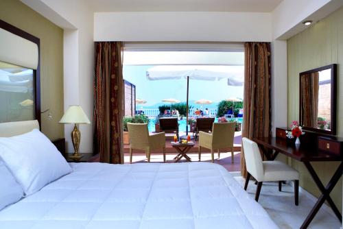 a bedroom with a bed and a desk and a balcony at Sunshine Corfu Hotel And Spa in Nisakion