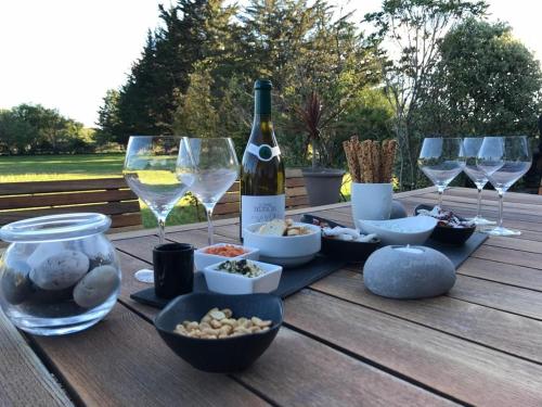 una mesa de madera con una botella de vino y copas de vino en Le clos de la lande vallée, en Bringal