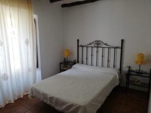 1 dormitorio con 1 cama con sábanas blancas y ventana en Apartamentos Rurales Lanteira en Lanteira