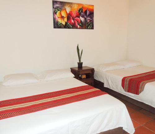 two beds in a room with a painting on the wall at Portoazul Casa de Playa in Puerto Colombia