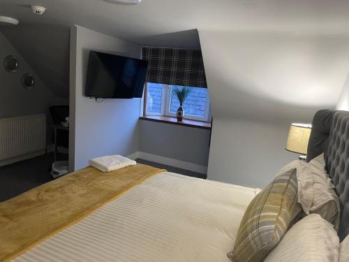 a bedroom with a bed and a tv on the wall at Commercial Hotel (Insch) in Insch