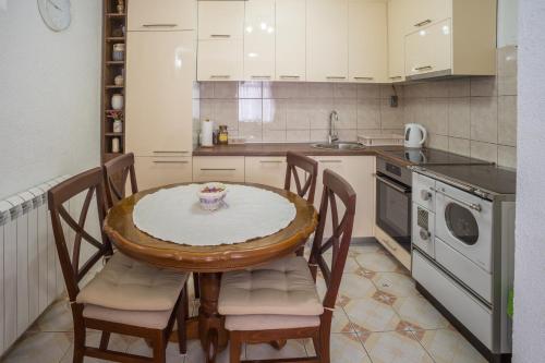 eine Küche mit einem Tisch mit Stühlen und einem Waschbecken in der Unterkunft Vojinovic Apartman in Žabljak