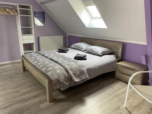 a bedroom with a large bed with purple walls at LE DOMAINE DES SAULES in Richebourg