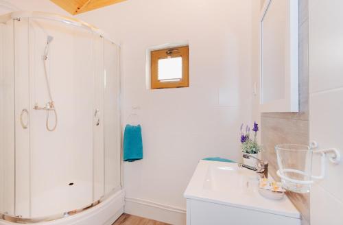 a white bathroom with a shower and a sink at Domki Dzika Róża in Darłowo