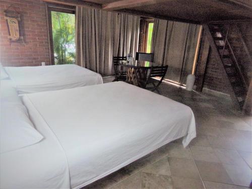 two beds in a room with a table and chairs at Hotel Casa de Lirio Diamante in Acapulco
