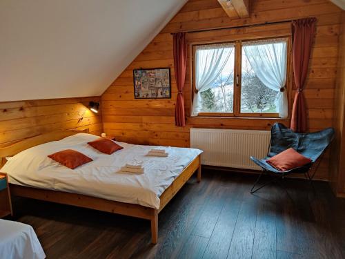 a bedroom with a bed and a chair and a window at Alpine Escape Studios in Măgura